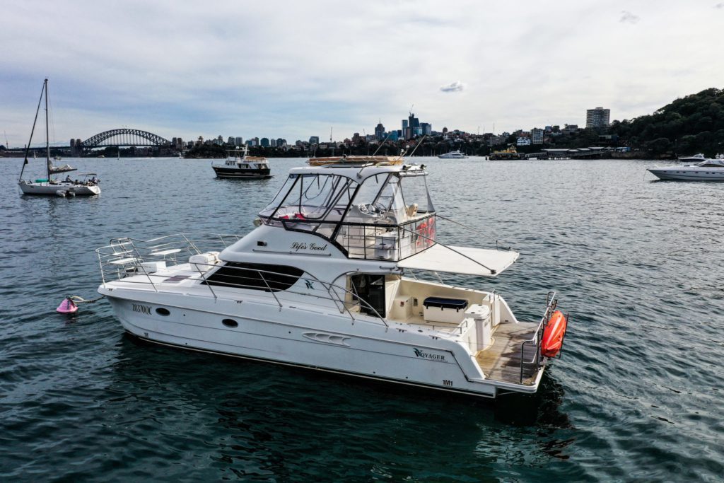 A private yacht charter named "Life's Good" floats on water with a cityscape and the Sydney Harbour Bridge in the background.