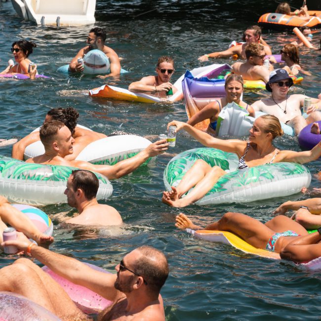 A group of people relaxing and socializing on inflatable rafts in a body of water on a sunny day, enjoying the ambiance reminiscent of a Sydney boat party hire.