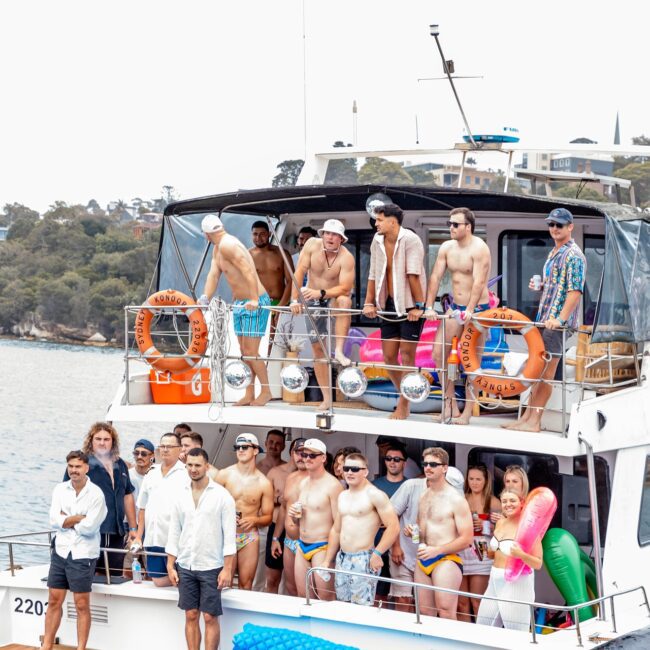 A lively social club gathers on the multi-level yacht, with people in swimwear posing and smiling. Some sport stylish sunglasses, while lifebuoys and inflatable floats add to the scene. The picturesque view of water and trees serves as a perfect backdrop for this exclusive gathering.