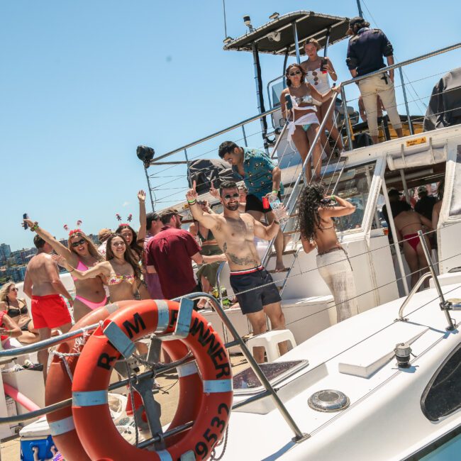 A lively group of people enjoying a party on a boat under the sunny sky. Some are on the deck, dancing and holding drinks. The city skyline is visible in the background, and colorful decorations are seen around.